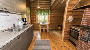 A rustic cabin interior with a kitchen, dining area, and fireplace.