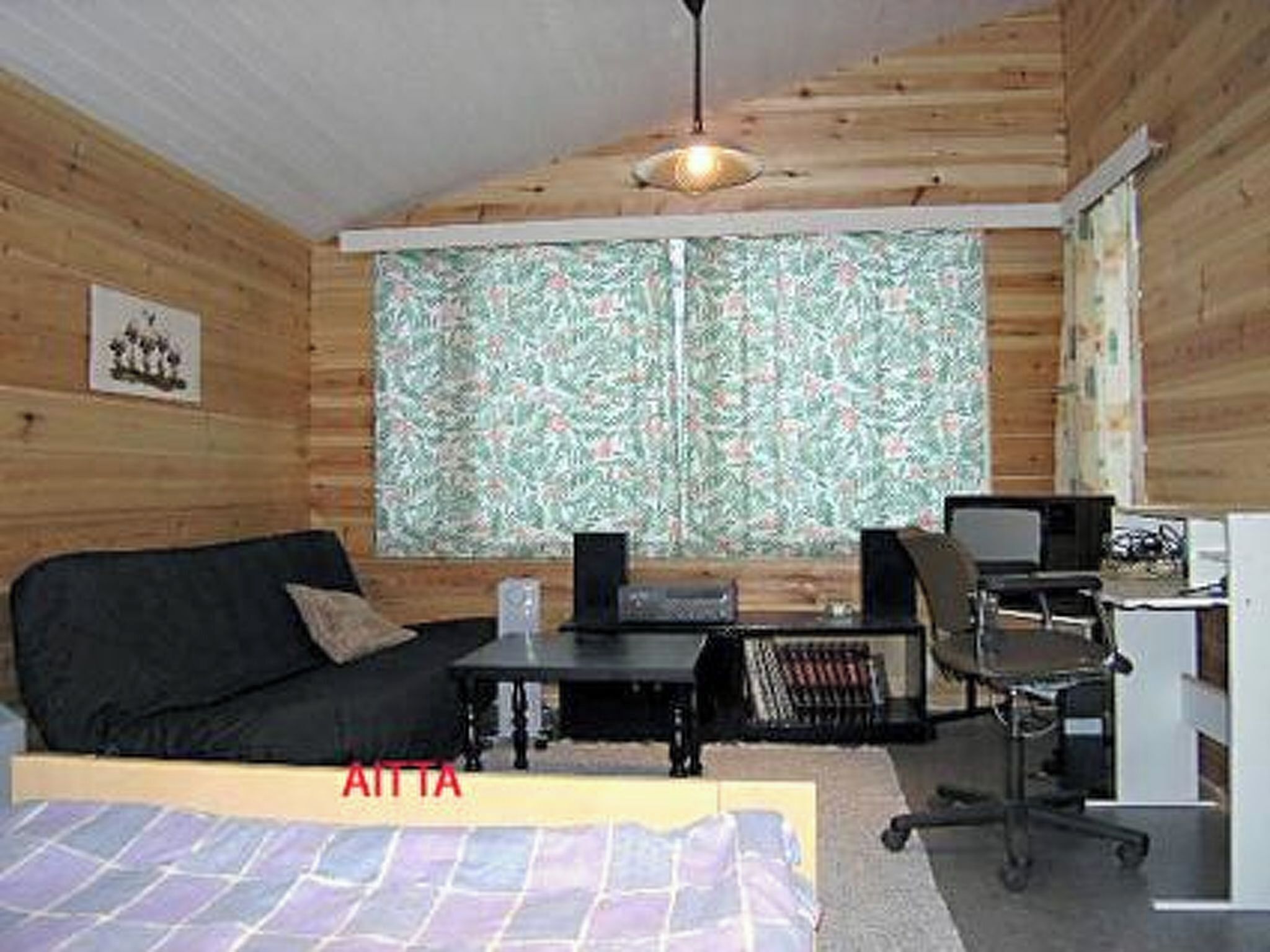 Una habitació acollidora amb un llit, un escriptori amb un ordinador i una cadira.