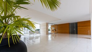 A spacious lobby with a large potted plant, a seating area, and a modern interior design. - Front Beach by Interhome (Calafell)