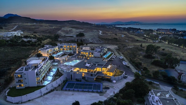 Un hotel moderno con varias construcciones, piscinas al aire libre y vista al mar.