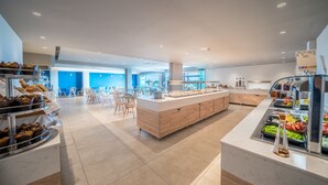 A modern breakfast area with a central island, seating, and various food stations. - Harmony Crest Resort& SPA (Kos)