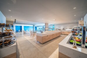A modern breakfast area with a central island, seating, and various food stations. - Harmony Crest Resort& SPA (Kos)