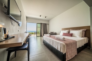 Una habitación de hotel moderna con una cama grande, un escritorio y vista al océano.