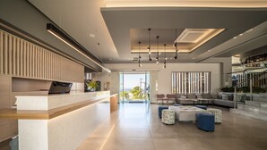 A modern interior with a reception desk, seating area, and a staircase leading to an upper level. - Harmony Crest Resort& SPA (Kos)