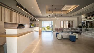 Ein modernes Interieur mit einer Rezeption, einer Sitzecke und einer Treppe zu einer oberen Ebene.