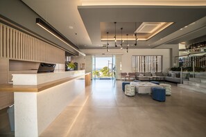 A modern interior with a reception desk, seating area, and a staircase leading to an upper level. - Harmony Crest Resort& SPA (Kos)