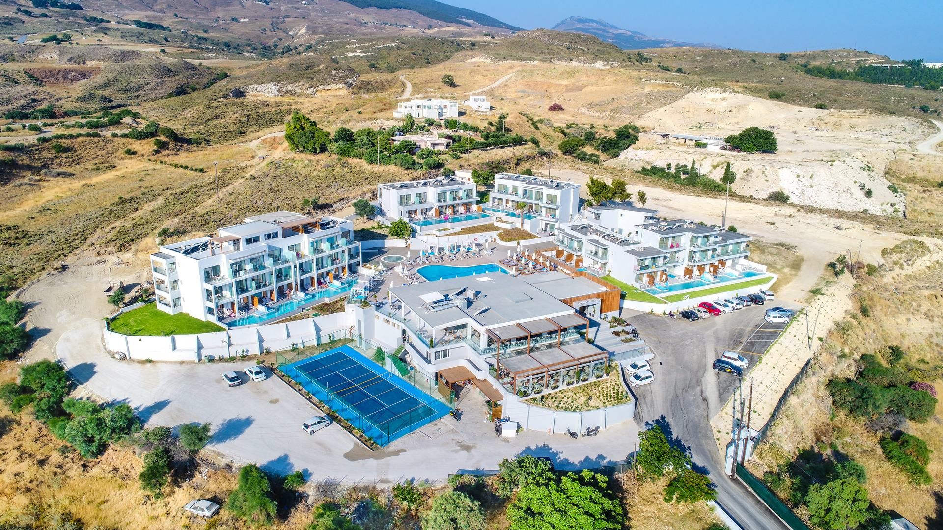 Ein modernes Resort mit mehreren Gebäuden, einem zentralen Pool und einem Parkplatz.