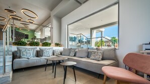 Un intérieur moderne avec un canapé, deux tables rondes et une chaise rose.