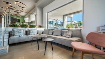 A modern interior with a sofa, two round tables, and a pink chair.