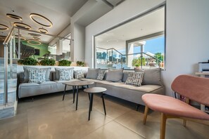A modern interior with a sofa, two round tables, and a pink chair. - Harmony Crest Resort& SPA (Kos)