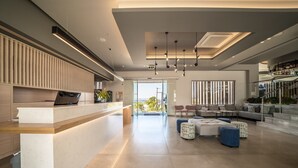 Un interior moderno con mostrador de recepción, zona de estar y una escalera que conduce a un nivel superior.