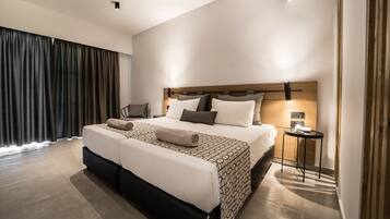 Ein modernes Hotelzimmer mit einem großen Bett, einem Nachttisch mit Lampe und Blick durch das Fenster nach draußen.