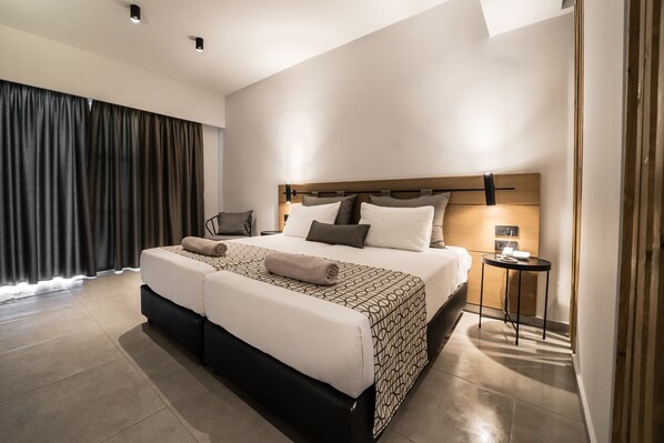 A modern hotel room with a large bed, a bedside table with a lamp, and a view of the outside through the window. - Harmony Crest Resort& SPA (Kos)
