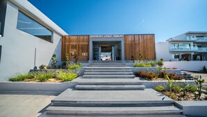 Un edificio moderno con fachada de madera, un cartel que dice 'HARMONY CRESC RESORT' y una serie de escalones de hormigón que conducen a la entrada.