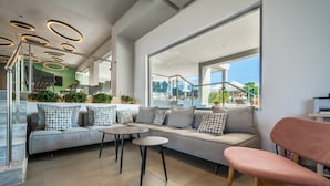 Un interior moderno con un sofá, dos mesas redondas y una silla rosa.
