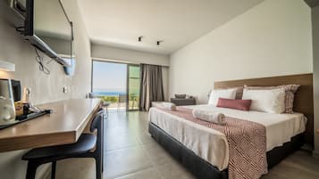 A modern hotel room with a large bed, a desk, and a view of the ocean.