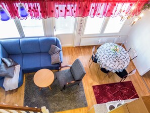 A living room with a blue sofa, a round wooden table, and a red patterned rug. - Point vale 4 as 3 by Interhome (Nilsiä)