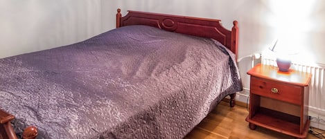 Une chambre à coucher avec un lit, une table de chevet, une lampe et un tableau au mur.