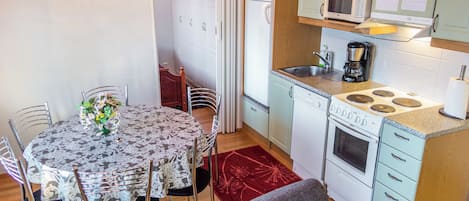 Una cucina compatta con zona pranzo, che include un tavolo con sedie, un forno a microonde, un fornello e pensili.