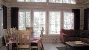 Una habitación con una mesa de comedor, sillas, un sofá y ventanas amplias.