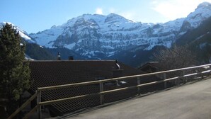 Une vue sur la montagne, avec une clôture en bois et un bâtiment doté d’un toit en pente.