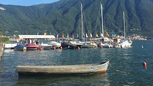 A marina with boats docked, a clear sky, and mountains in the background.