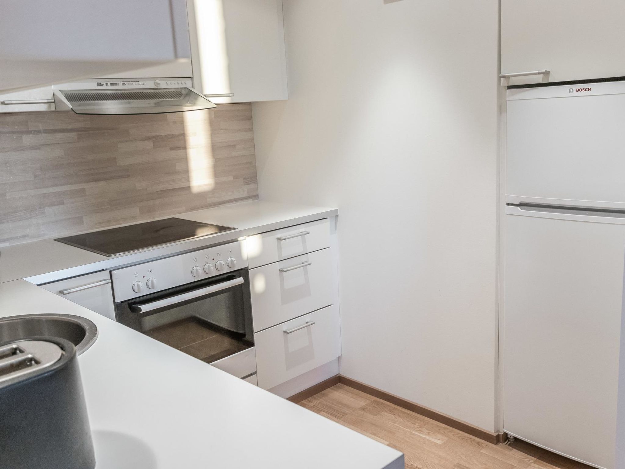 Una cocina moderna con un refrigerador Bosch, un horno empotrado y una placa de cocina.