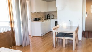 A modern kitchen with white cabinets, a dining table with chairs, and a large window with curtains.