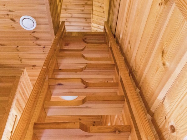 A wooden staircase with a handrail, leading to a ceiling with a circular light fixture.