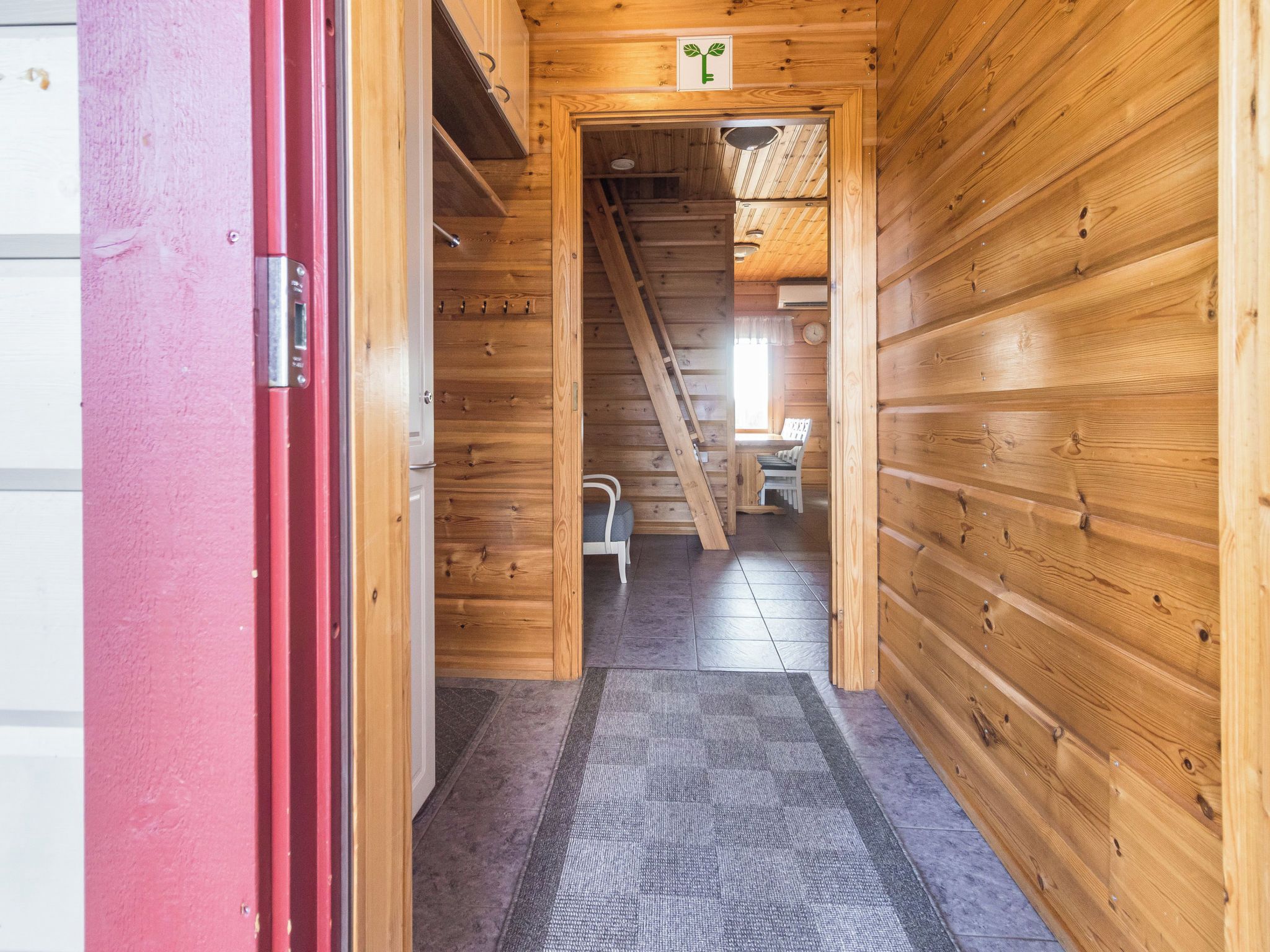 Pasillo interior de madera que conduce a una habitación con cama y ventana.