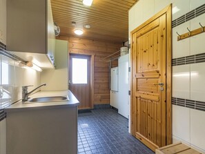 A compact kitchen with a wooden door, a sink, and a refrigerator.