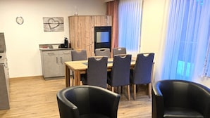 Moderni keittiö, jossa on puinen kaappi, ruokapöytä kuudella tuolilla ja suuri ikkuna, jossa on ohuet verhot.
