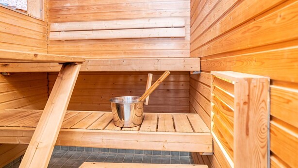 Eine Holzsauna mit einem Metallkübel und hölzernen Bänken.