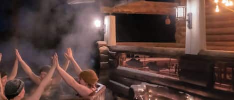 A hot tub area with wooden benches and a stone wall.
