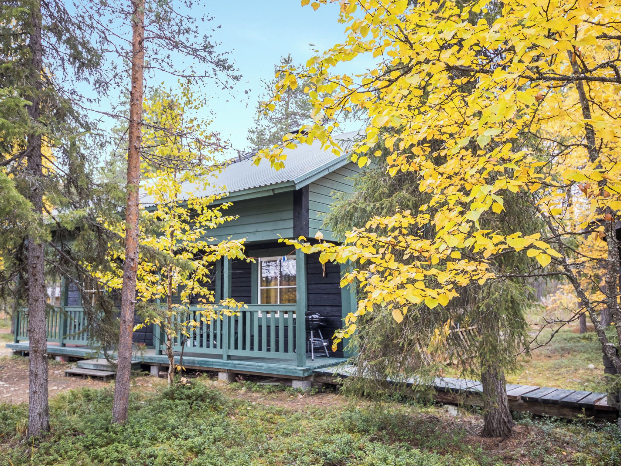 Eine Hütte mit Veranda, umgeben von Bäumen mit gelben Blättern.
