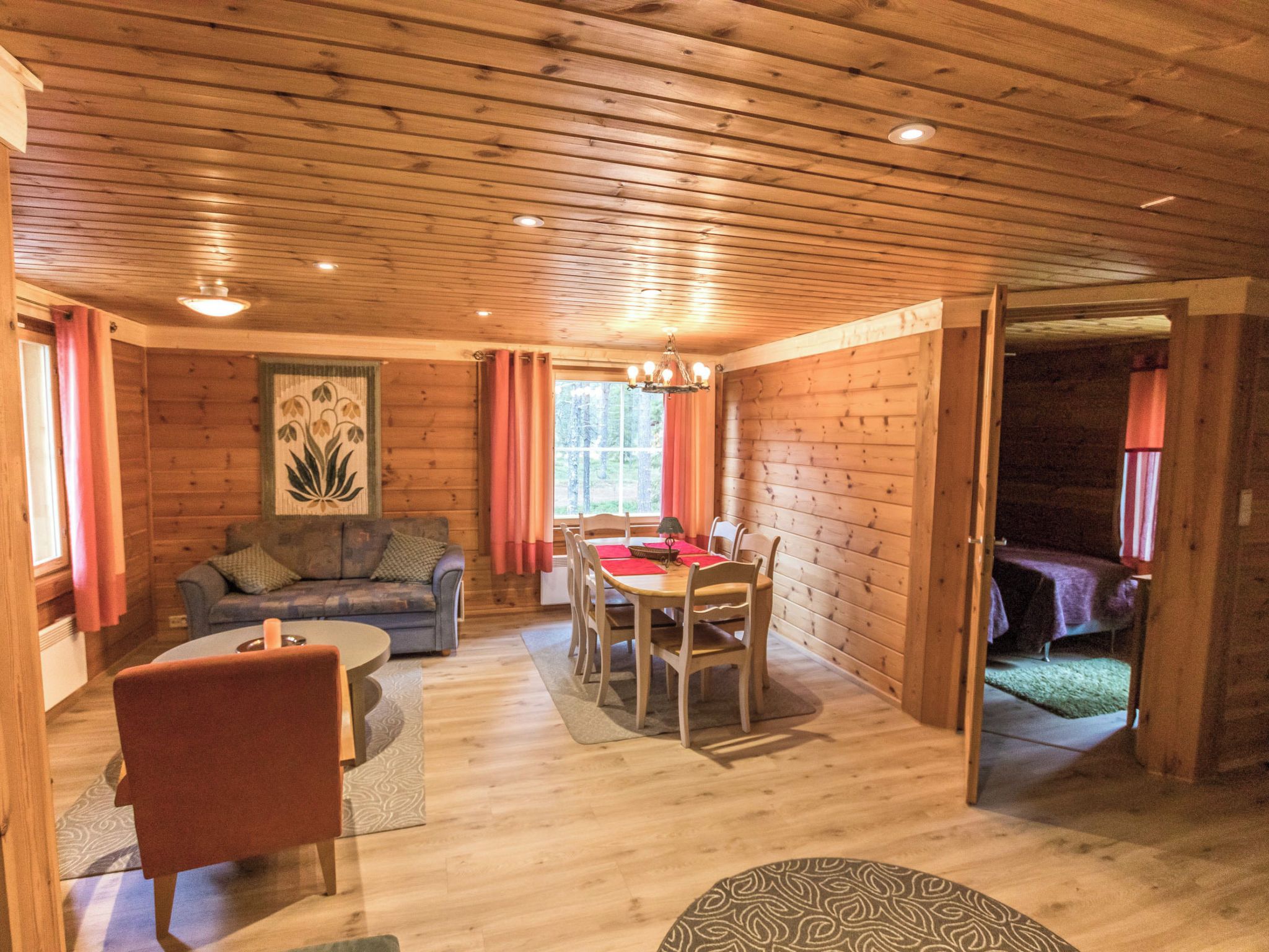 Interior acolhedor de uma cabana, com área de jantar, sofá e poltrona.