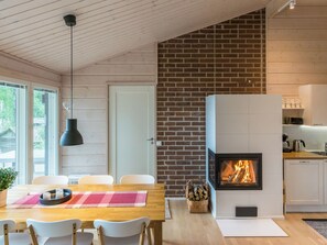 Eine moderne Küche mit integriertem Kamin, Holzboden und einem Essbereich mit Tisch und Stühlen.