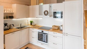 Une cuisine moderne avec des armoires blanches, un plan de travail en bois, un four encastré, un four à micro-ondes et un évier.