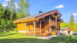 A log cabin with a porch, a chimney, and a small adjacent shed. - Rinne-expertti by Interhome (Ruokolahti)