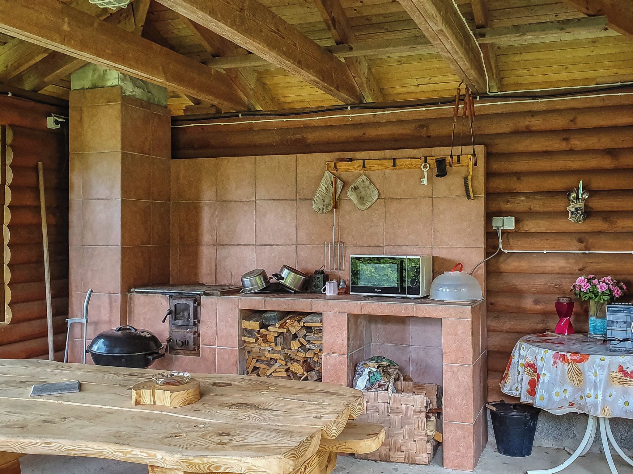 A rustic wooden cabin with a tiled fireplace, a television, and a table with a floral tablecloth.