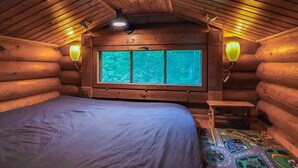 A log cabin bedroom with a bed, a window, and two wall-mounted lamps. - Rinne-expertti by Interhome (Ruokolahti)