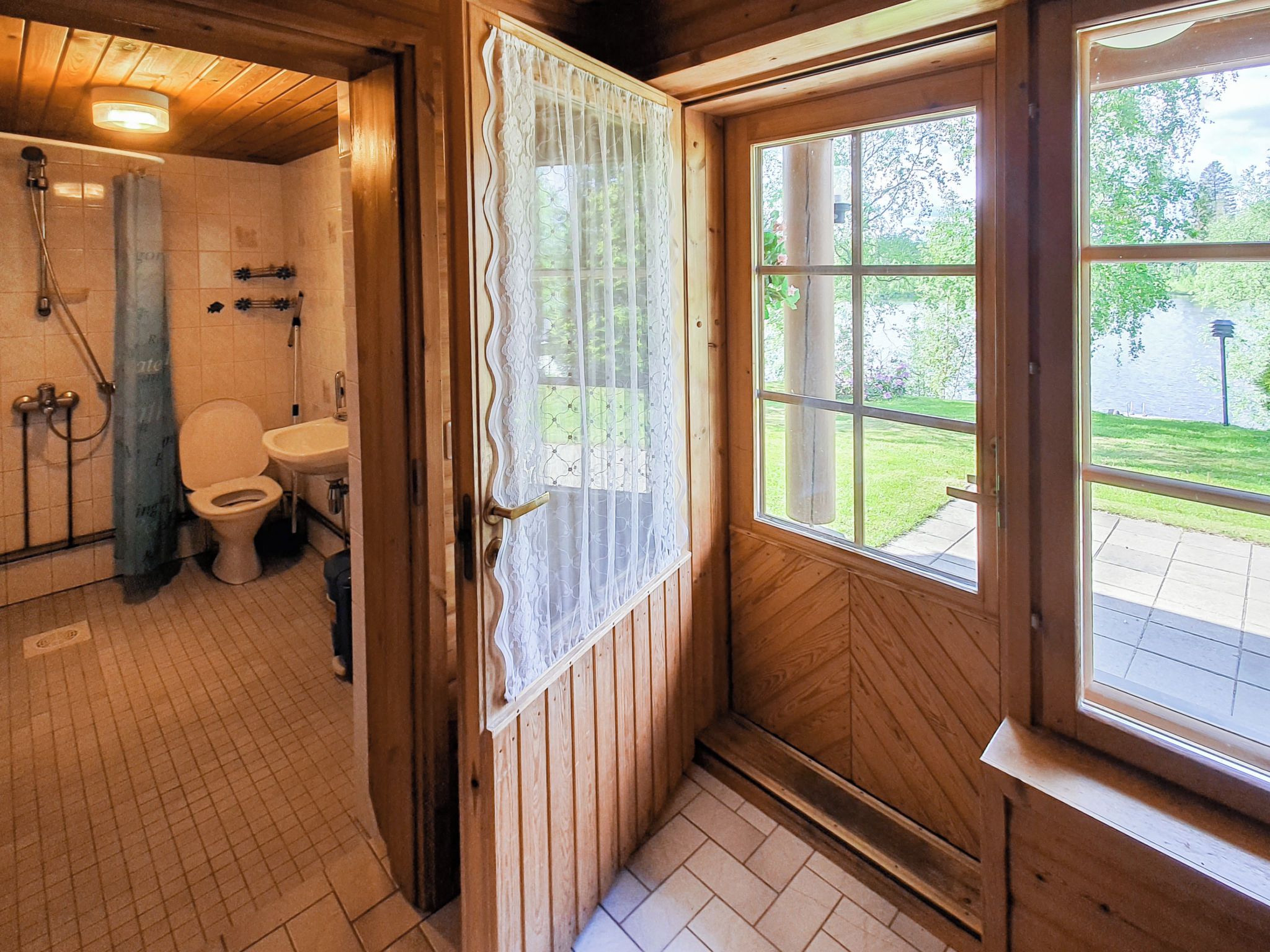 A wooden bathroom with a toilet, sink, and shower.