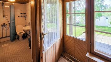 A wooden bathroom with a toilet, sink, and shower.