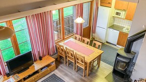 Un espacio habitable compacto con comedor, cocina y estufa de leña.