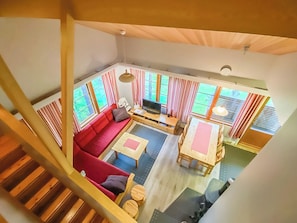 Uma sala de estar ampla com um sofá vermelho, uma mesa de centro de madeira e uma televisão.