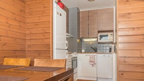 Eine kleine Küche mit Holzwänden, einem Esstisch mit zwei Stühlen, einer Mikrowelle, einem Herd und einem Geschirrspüler.