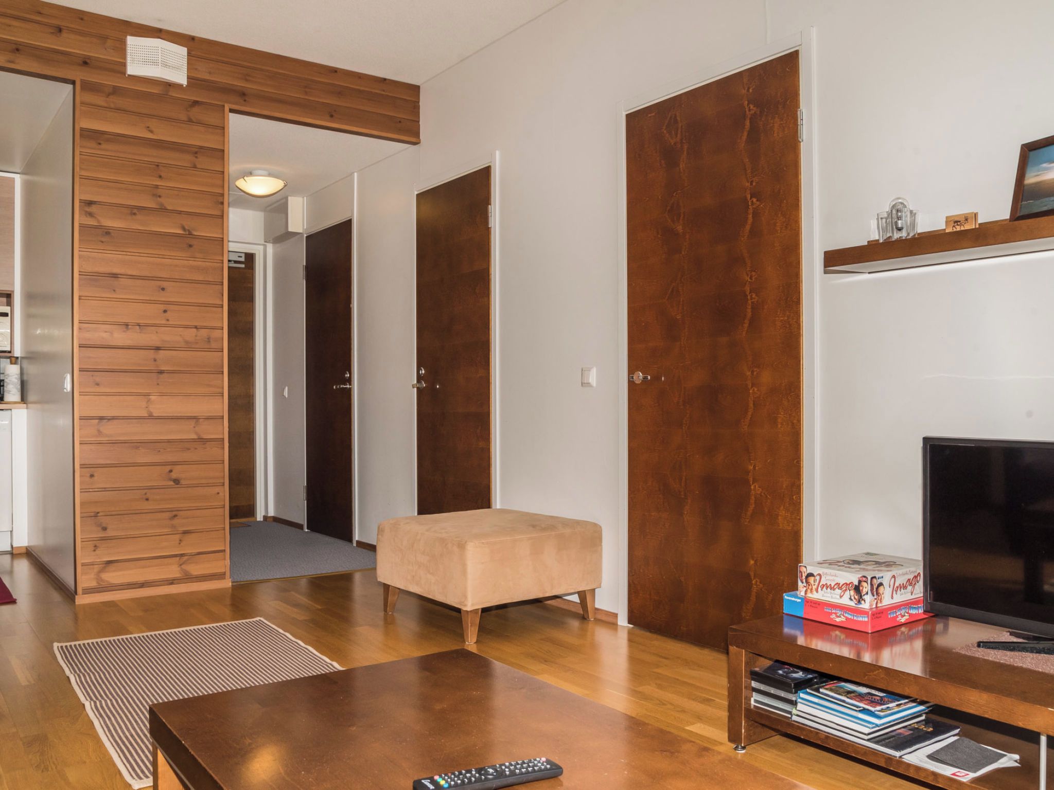 Una sala de estar moderna con un banco de madera, un televisor y una estantería.