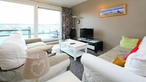 Una sala de estar moderna con un sofá, una mesa de centro, un televisor y un balcón con vistas.
