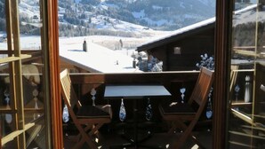 Une terrasse en bois avec une table et des chaises, offrant une vue sur un paysage montagneux enneigé.