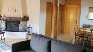 Un salon chaleureux avec une cheminée, un canapé et un coin repas agrémenté de meubles en bois.